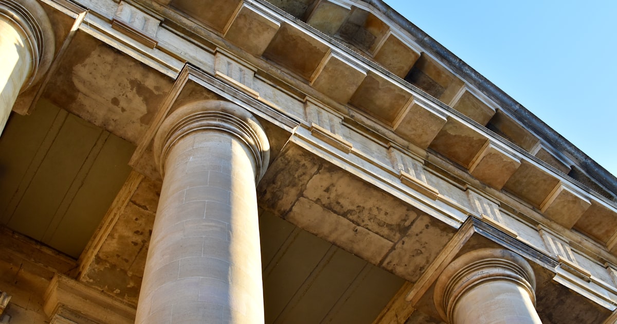 a tall building with columns and a clock on the top of it