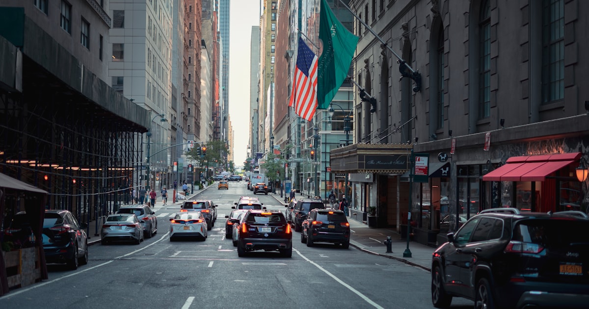 cars on road between high rise buildings during daytime