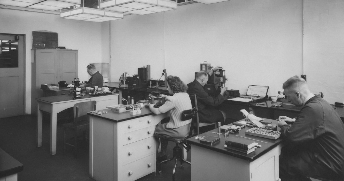 a black and white photo of people working in an office