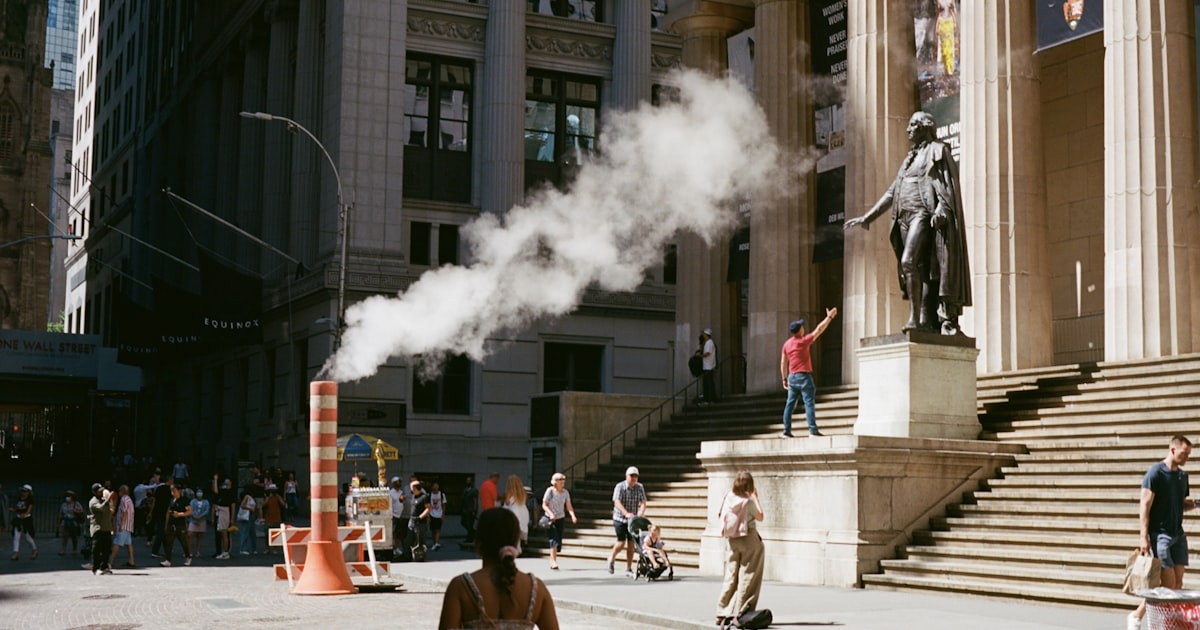 a woman walking down a street next to a tall building