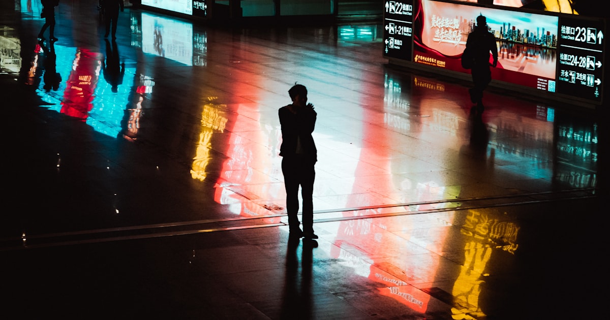 silhouette of person walking on sidewalk during night time