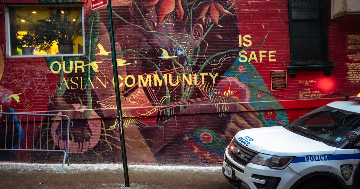 Mural with "our asian community is safe" and police car.