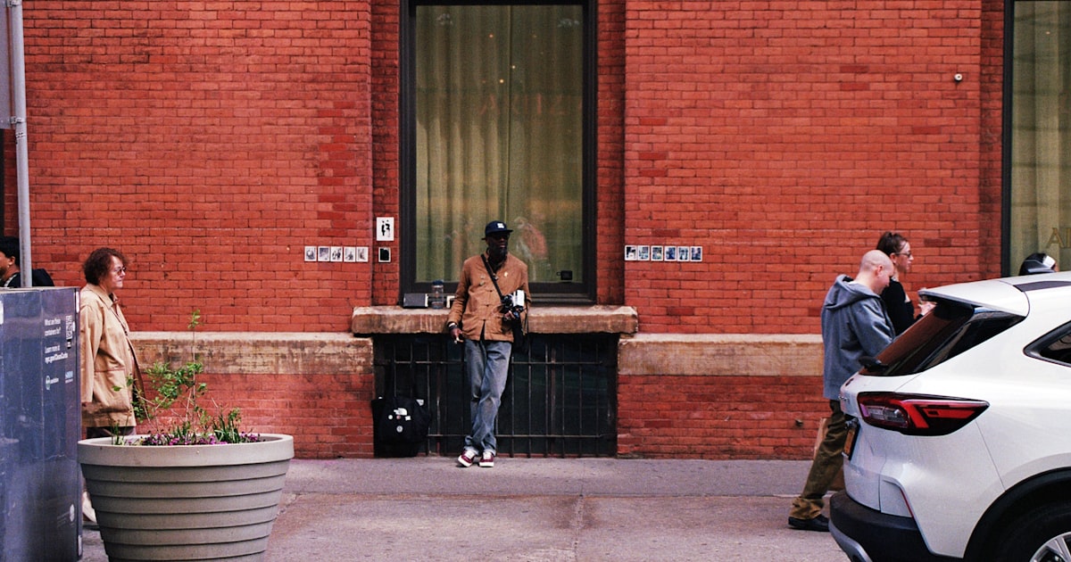 People on a brick wall sidewalk with a white car