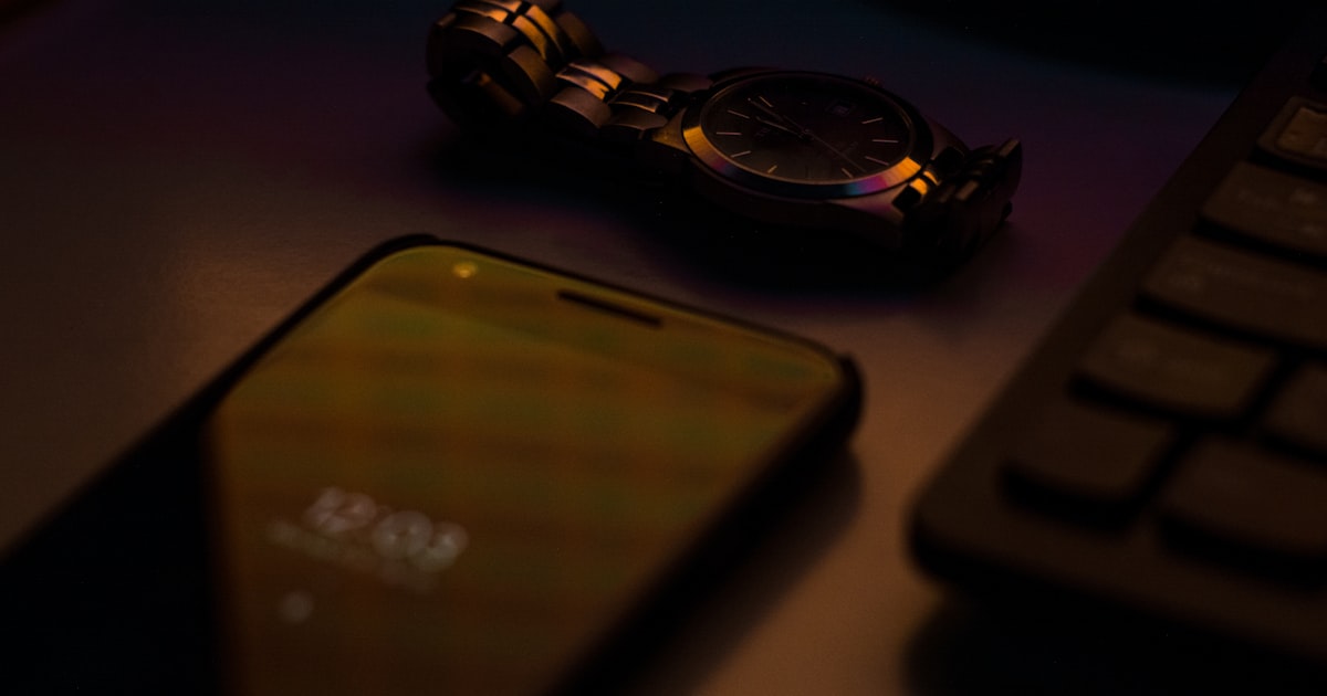 smartphone beside keyboard and watch