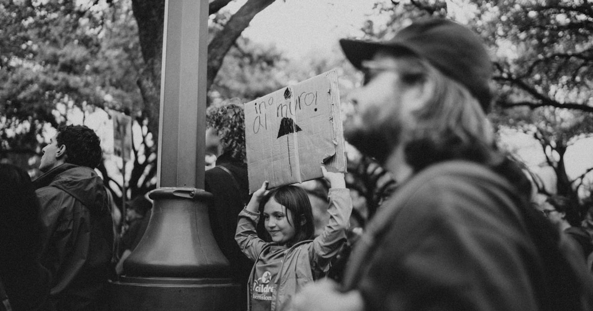 A young girl holds a sign in a crowd