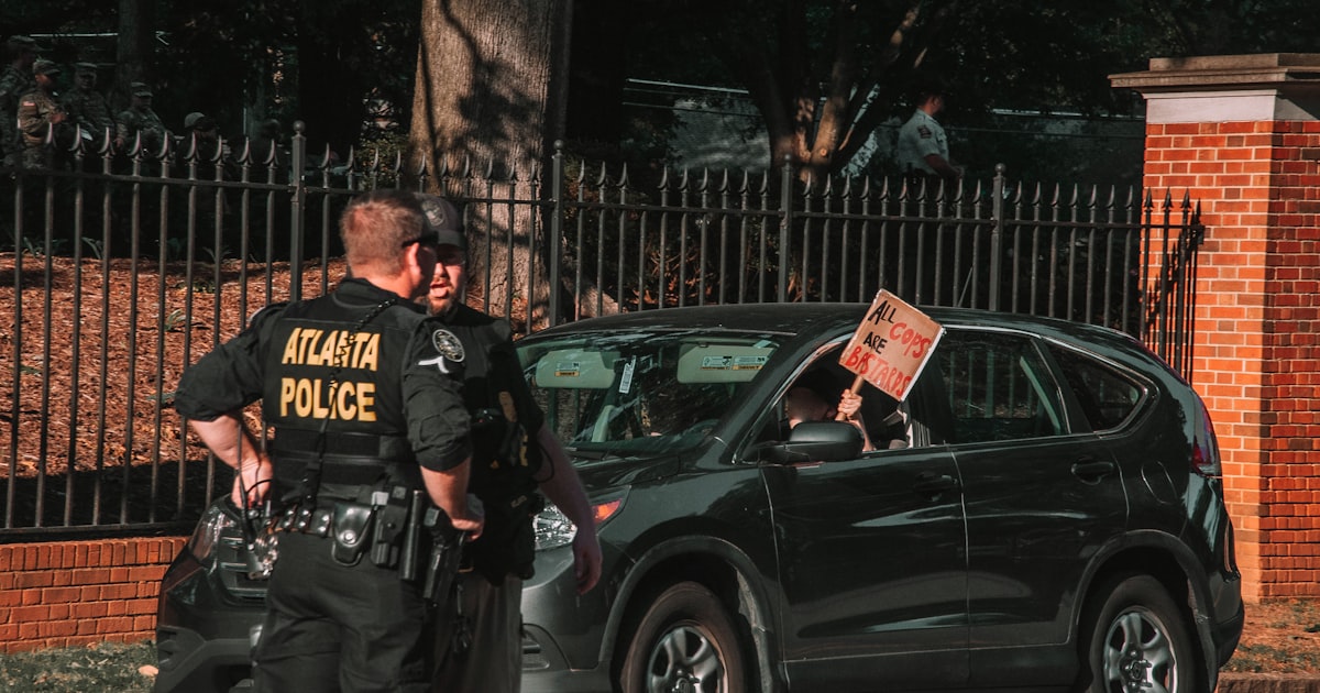 man in black and white crew neck t-shirt and black pants standing beside black suv