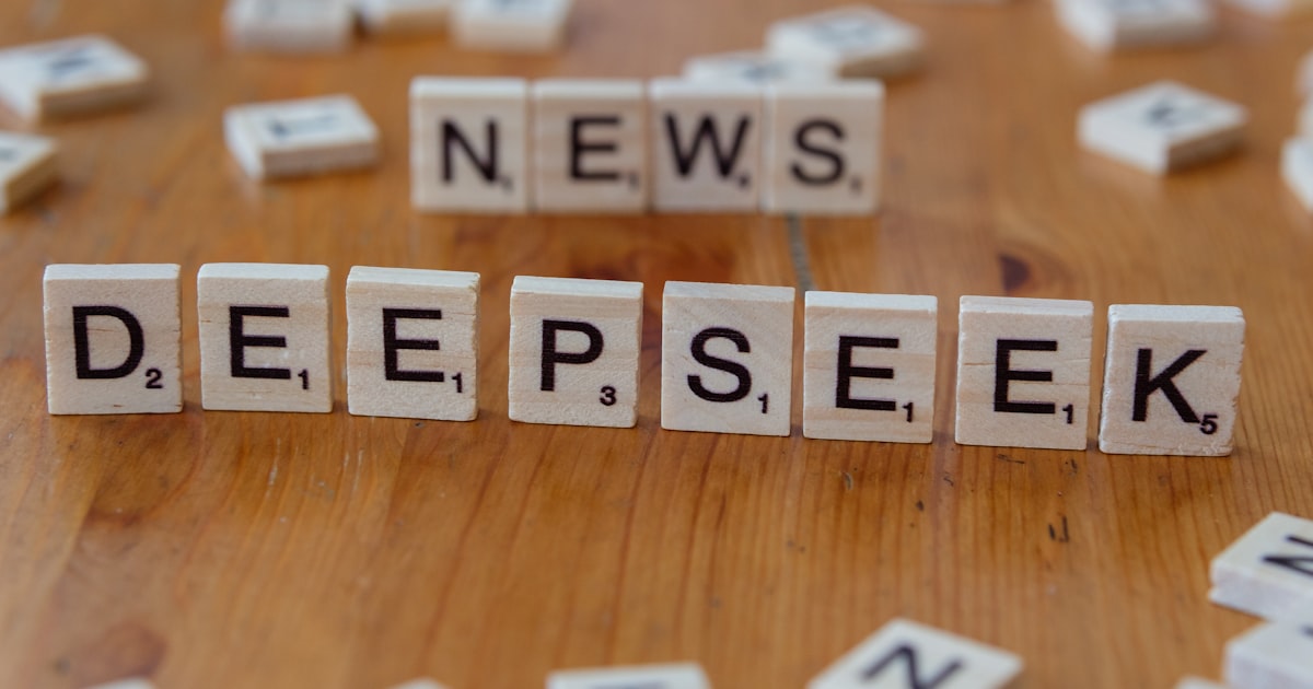 A wooden table topped with scrabble tiles spelling news and deep seek