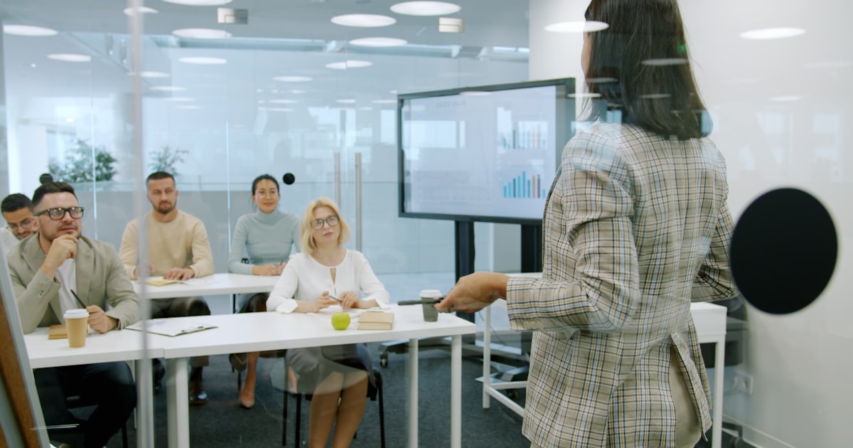 Woman presenting to an attentive audience in a modern office.
