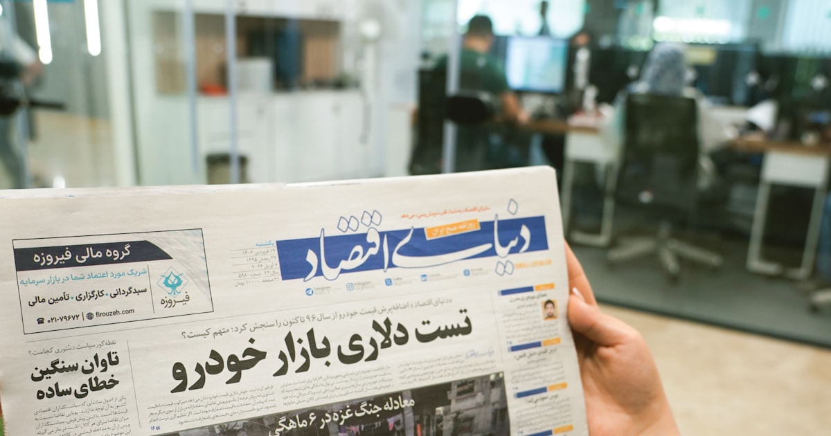 a person holding up a newspaper with arabic writing