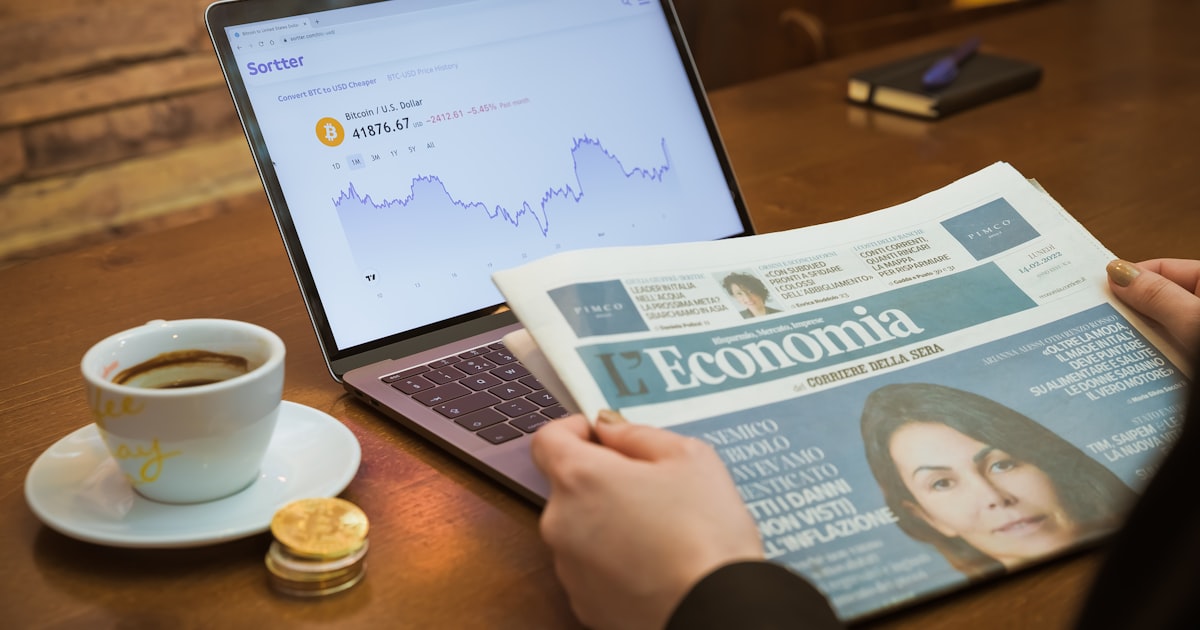 a person reading a newspaper next to a cup of coffee