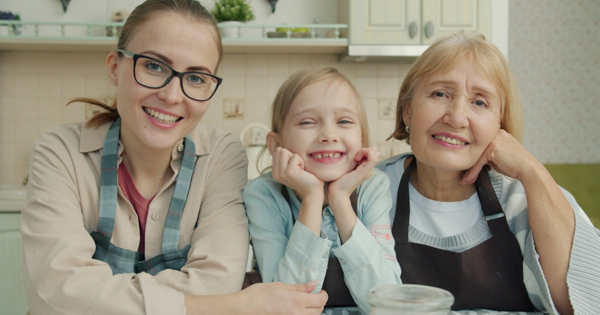 Three smiling women of different ages in a kitchen.