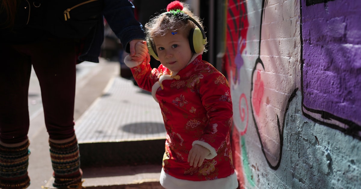Young girl in red coat with earmuffs near graffiti wall
