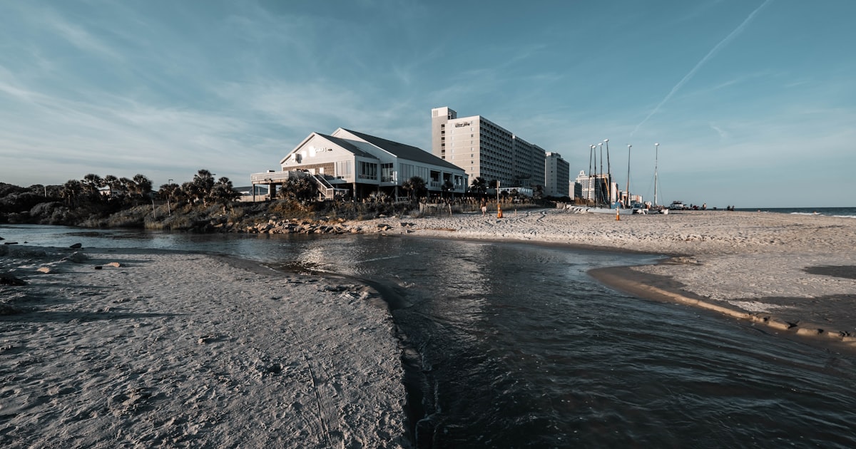 white and gray concrete building near body of water under blue sky during daytime