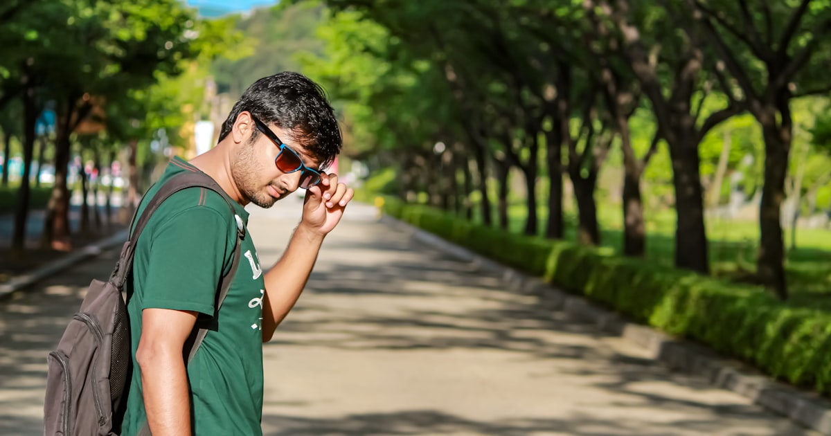 a man in a green shirt is talking on a cell phone
