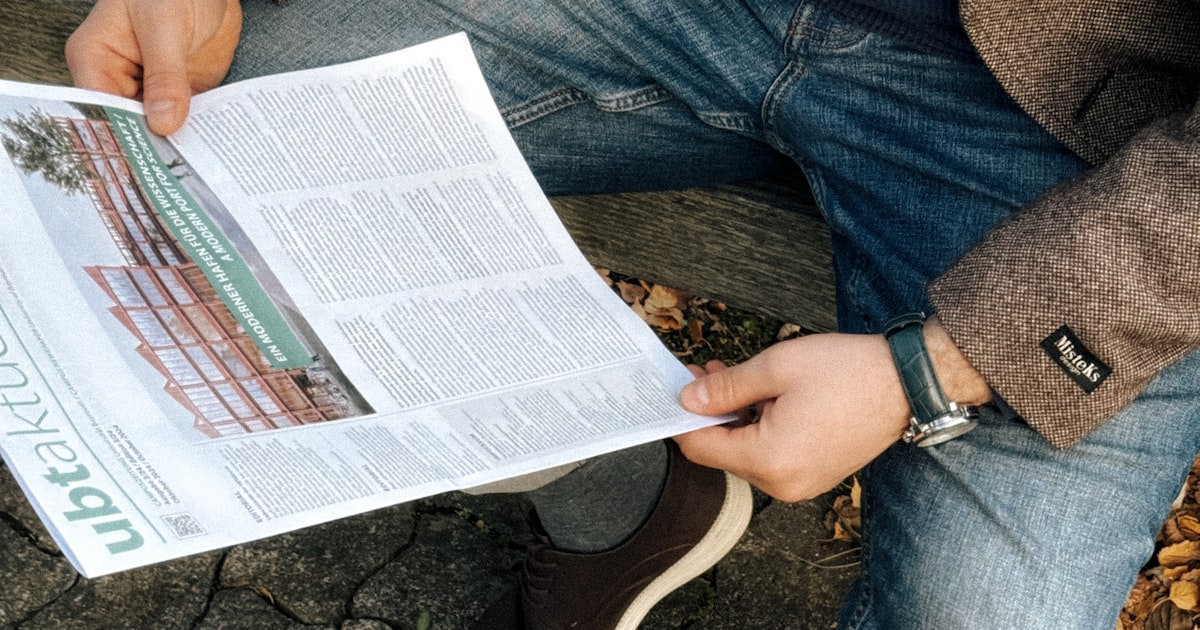 A man sitting on the ground reading a newspaper