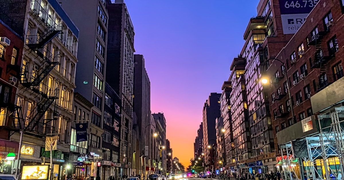cars on road between high rise buildings during night time
