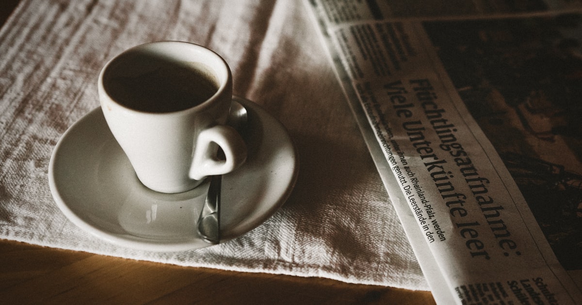 teacup on saucer near newspaper