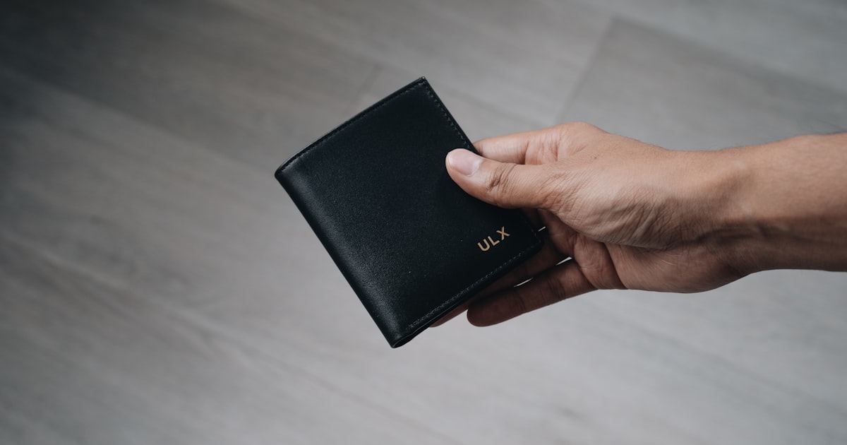 person holding black leather bifold wallet