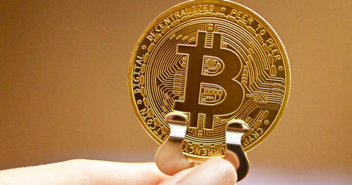 a person holding a bit coin in their hand