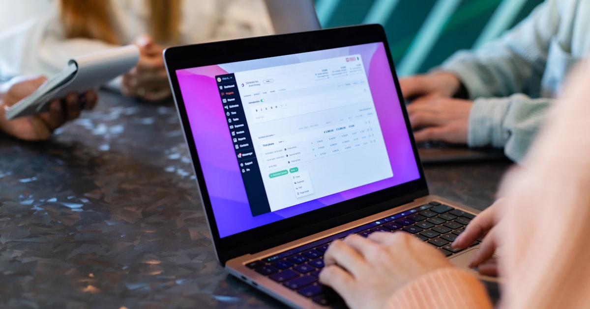 a group of people sitting at a table with laptops