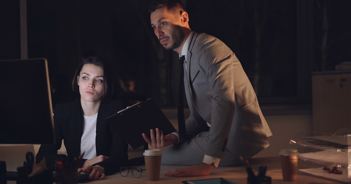 Two colleagues working late in a dimly lit office.