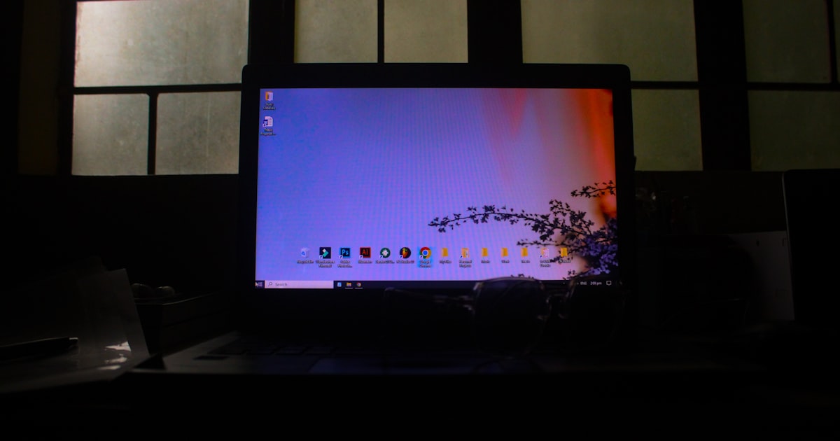 A laptop displaying a colorful desktop in a dark room.