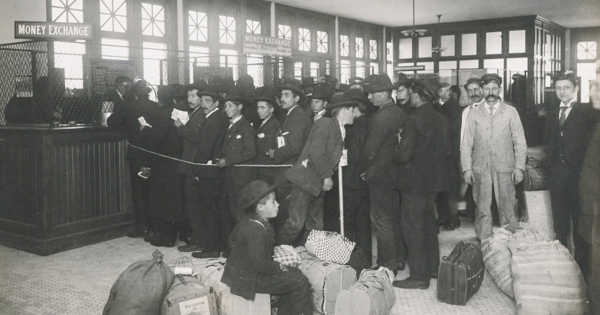 grayscale photo of a group of immigrants with bags inside
