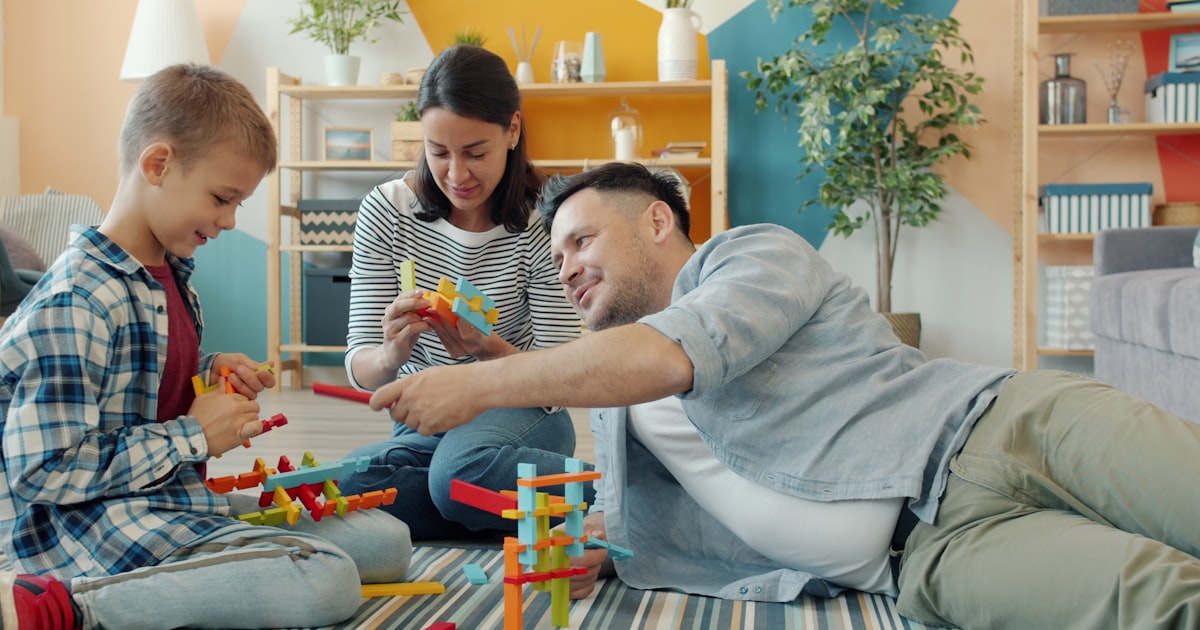 Family building with colorful toy blocks together on floor.