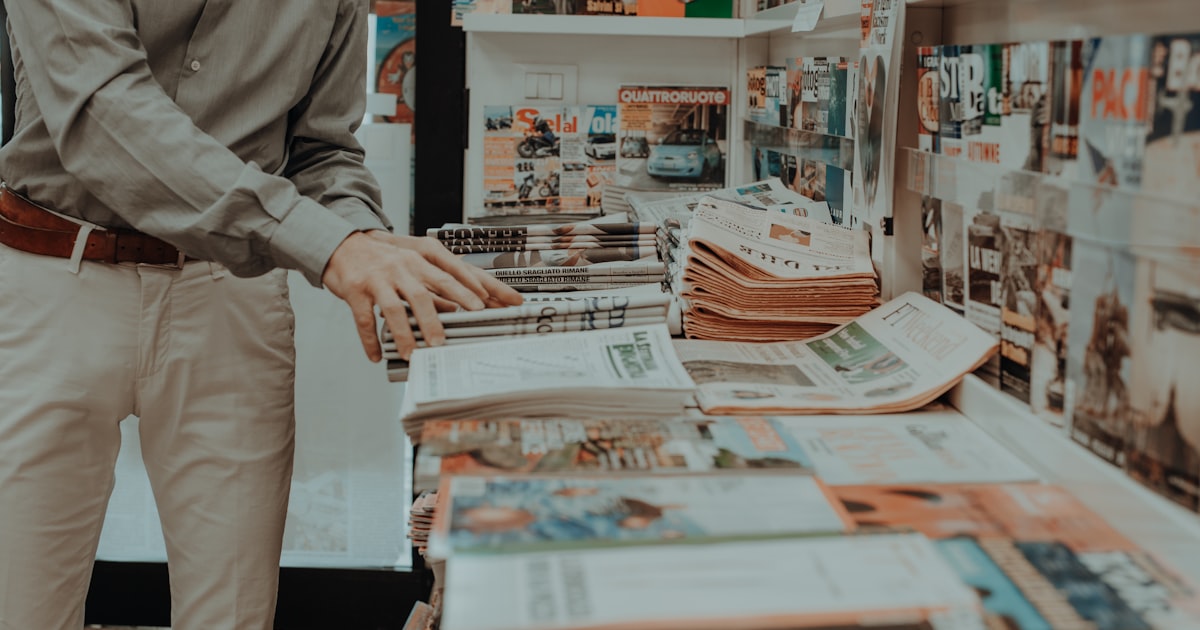 a man standing in front of a pile of magazines