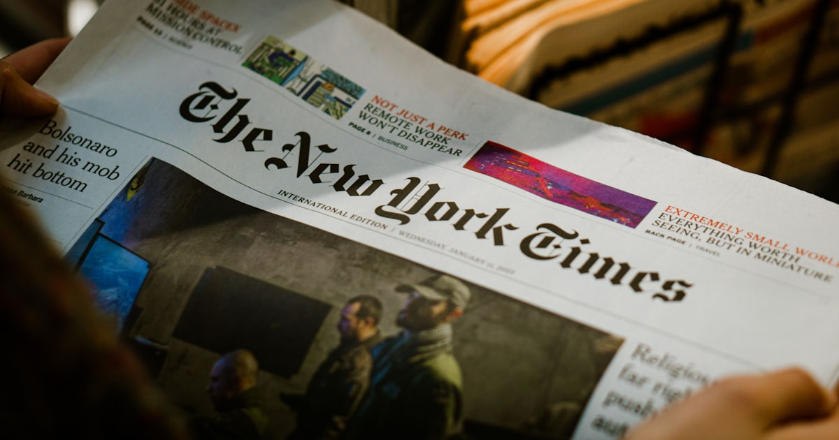 a person reading a newspaper with the new york times on it