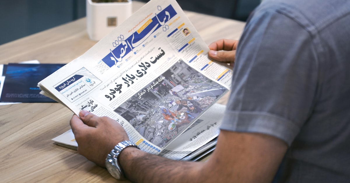 a man sitting at a table reading a newspaper