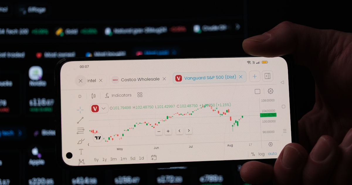 A person holding a business card in front of a computer screen