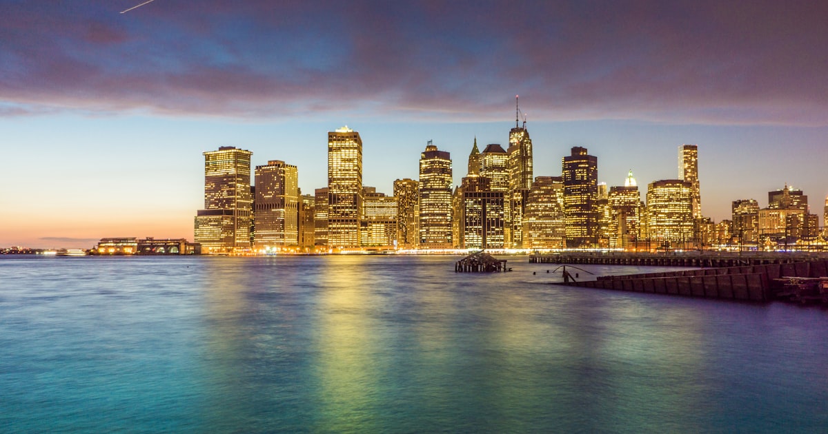 city skyline across body of water during night time