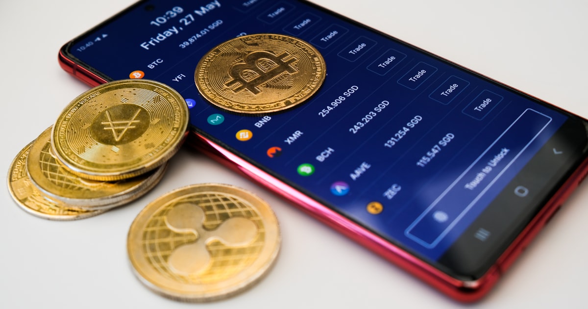 a cell phone with a bitcoin on it next to a pile of coins