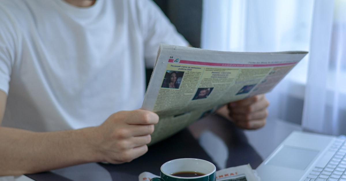 a man sitting at a table reading a newspaper