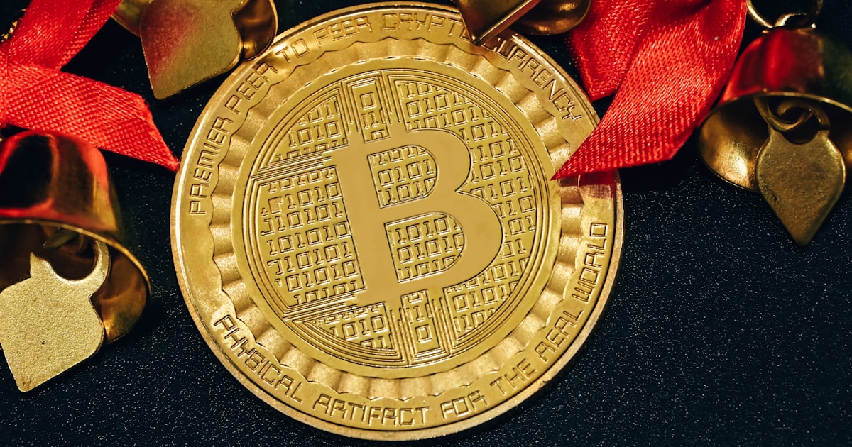 a gold bit coin with a red ribbon around it