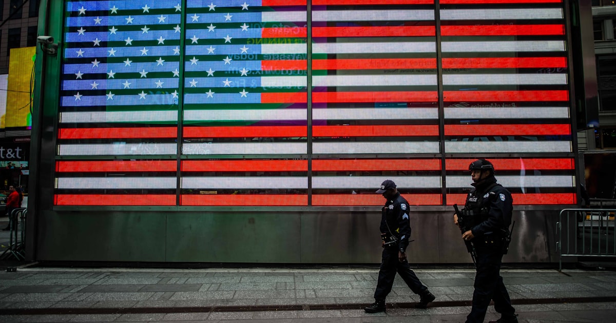 two man walks near USA flag wall