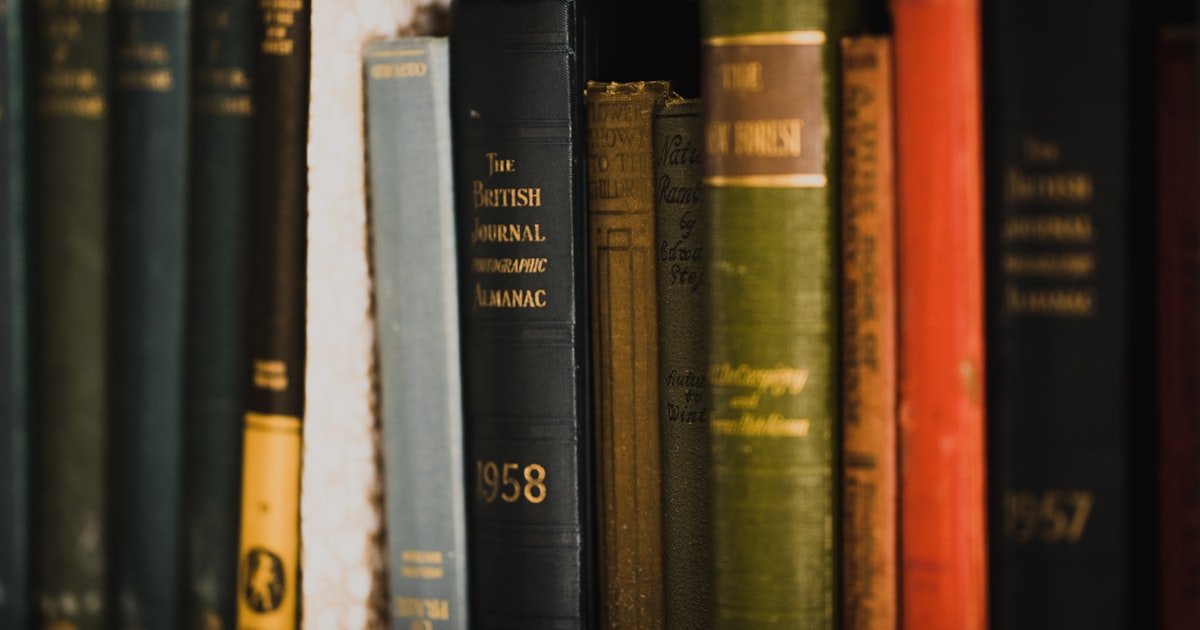 piled books on brown wooden shelf