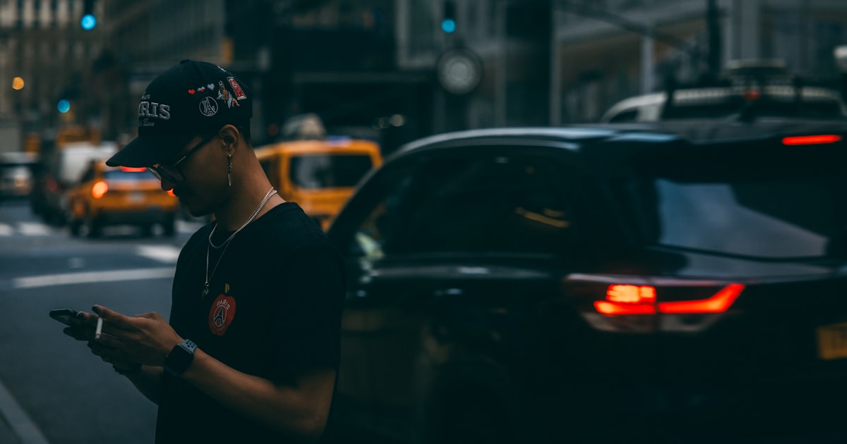 a man standing on the side of a street holding a cell phone