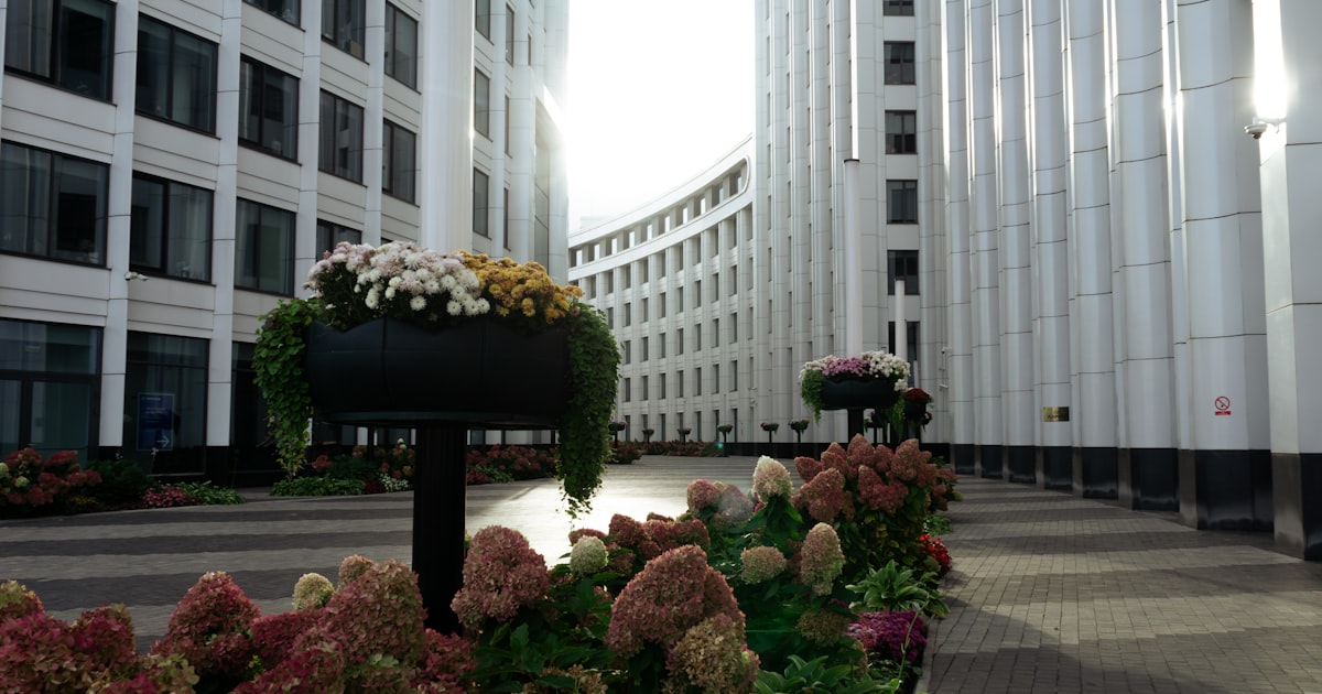 Modern office buildings with flower planters in courtyard.