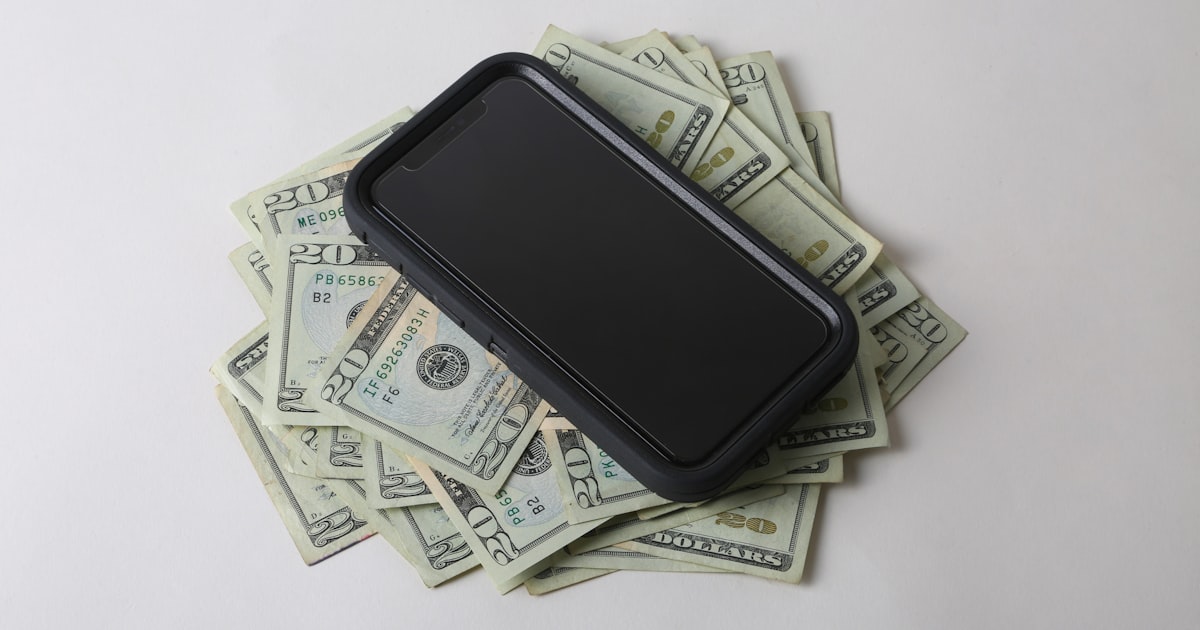 a cell phone sitting on top of a pile of money