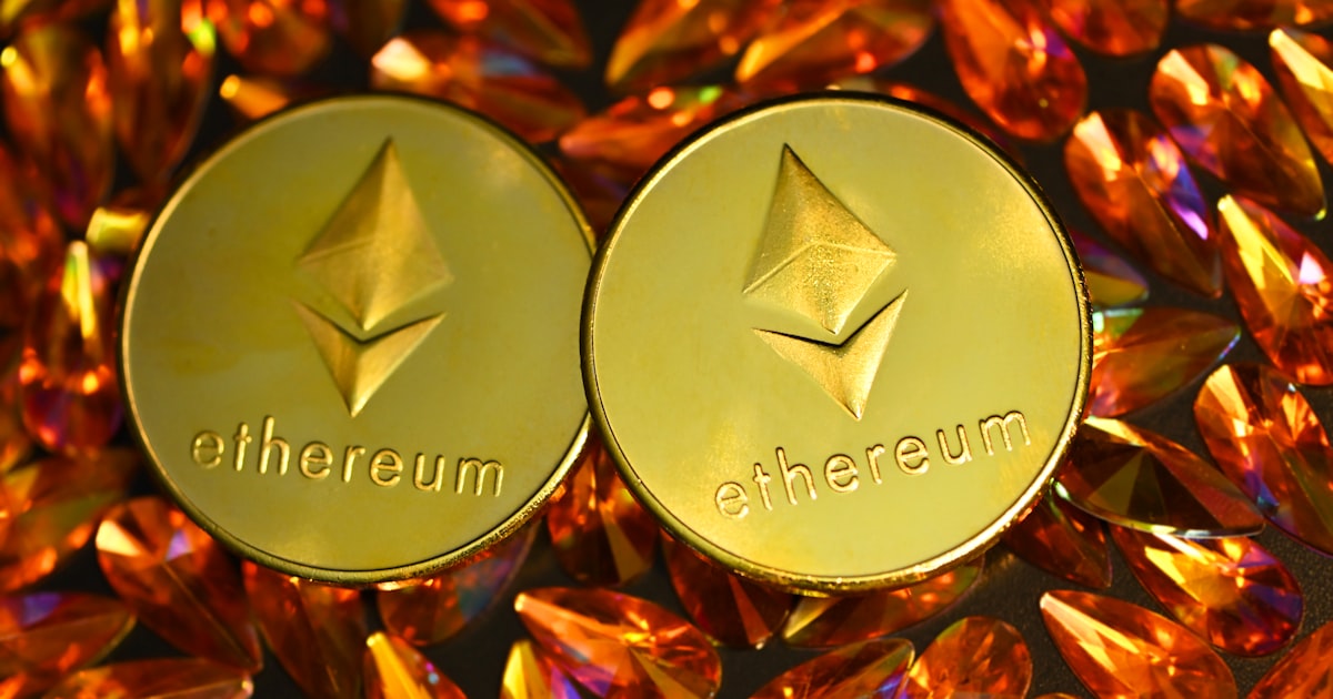 two gold ethereum tokens sitting on top of a pile of crystals