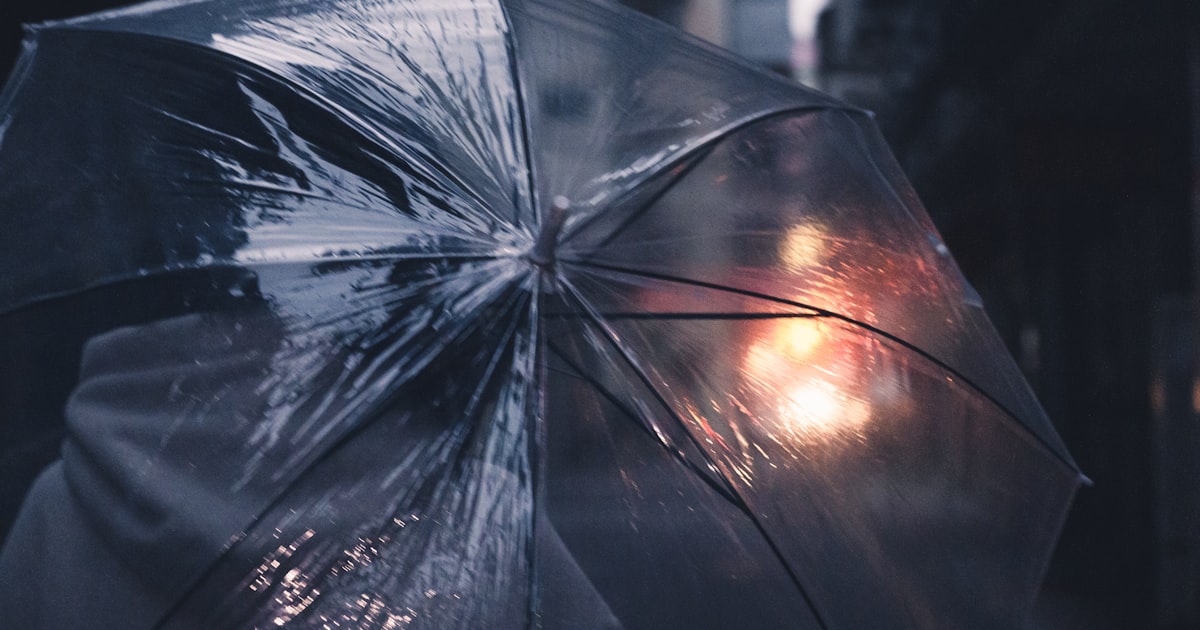 a person holding a clear umbrella in the rain