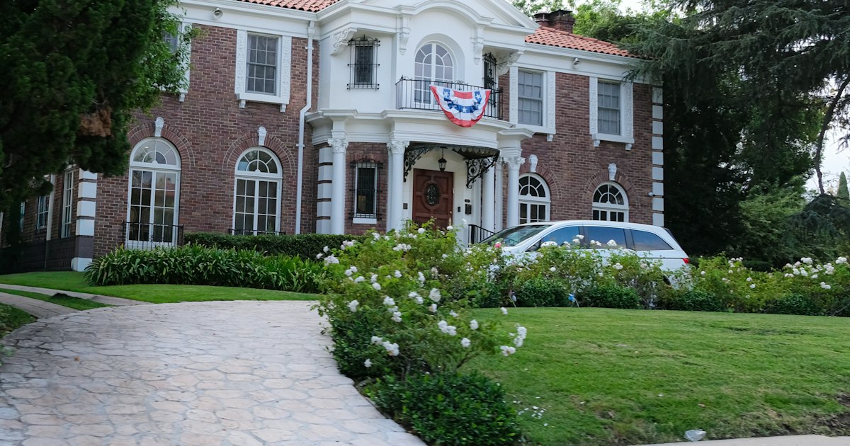 Large brick house with white trim and a car