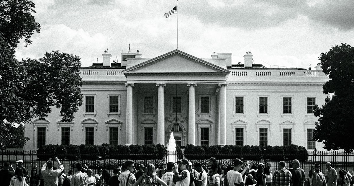 The white house stands with people gathered nearby.