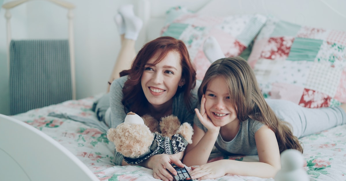 Mother and daughter smile while watching television.