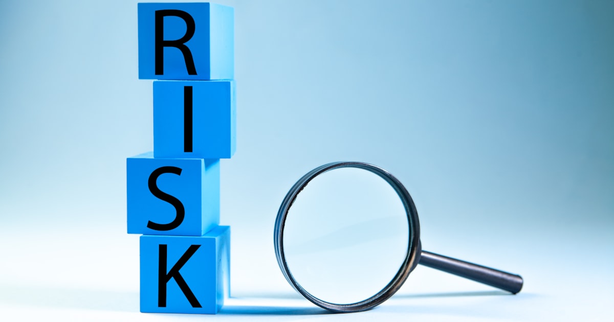 Blue blocks spelling risk next to a magnifying glass.